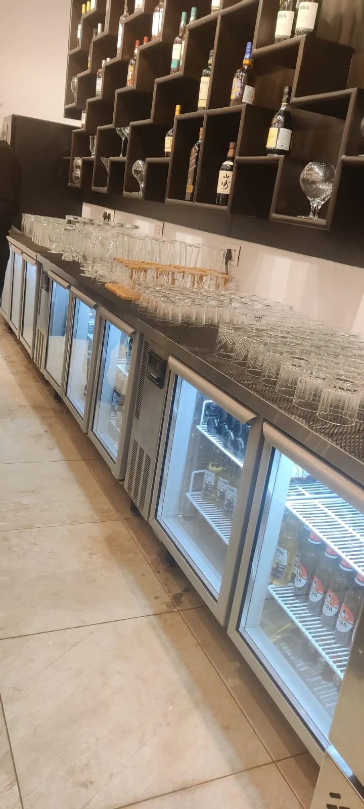 Glass door bottle coolers along a bar back counter