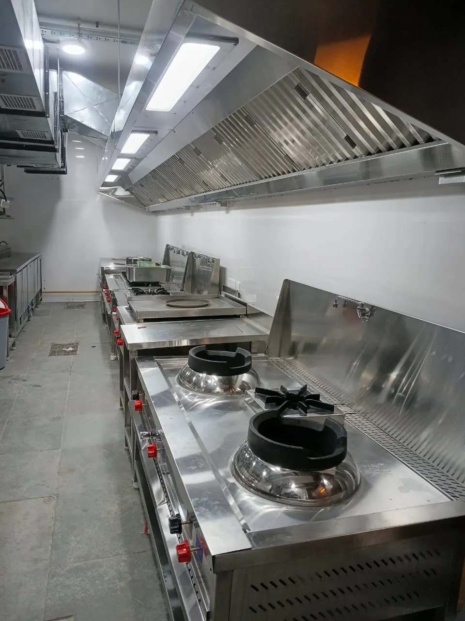 Two wok Chinese cooking range installed under a long exhaust hood