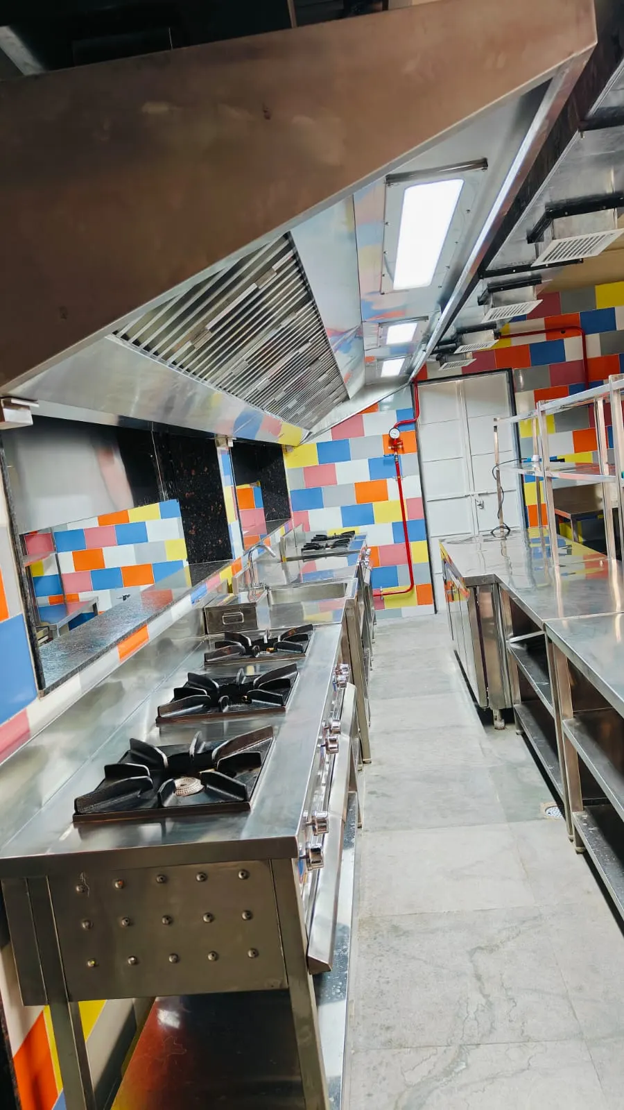 Exhaust hood over a gas burner line in a tiled kitchen