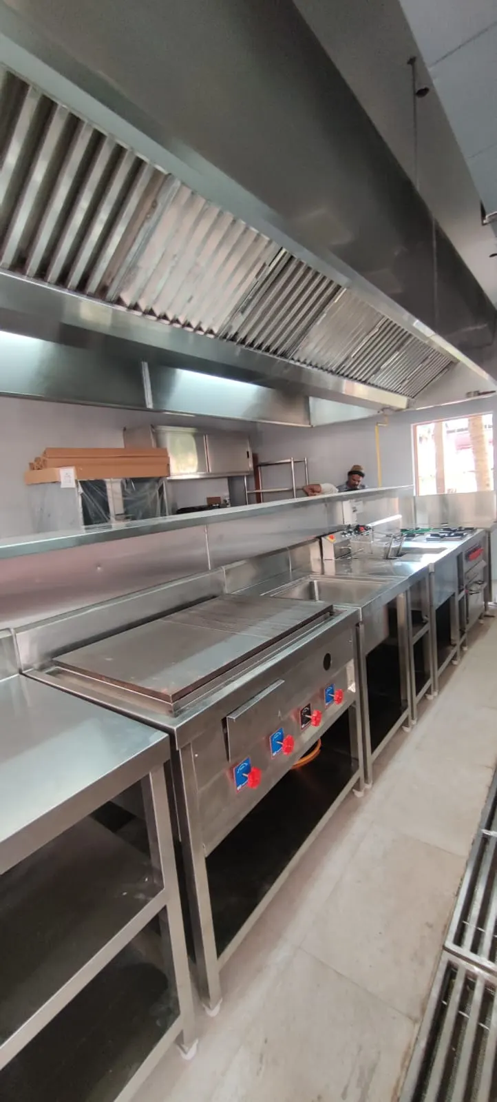 Wall exhaust hood over a griddle and range line