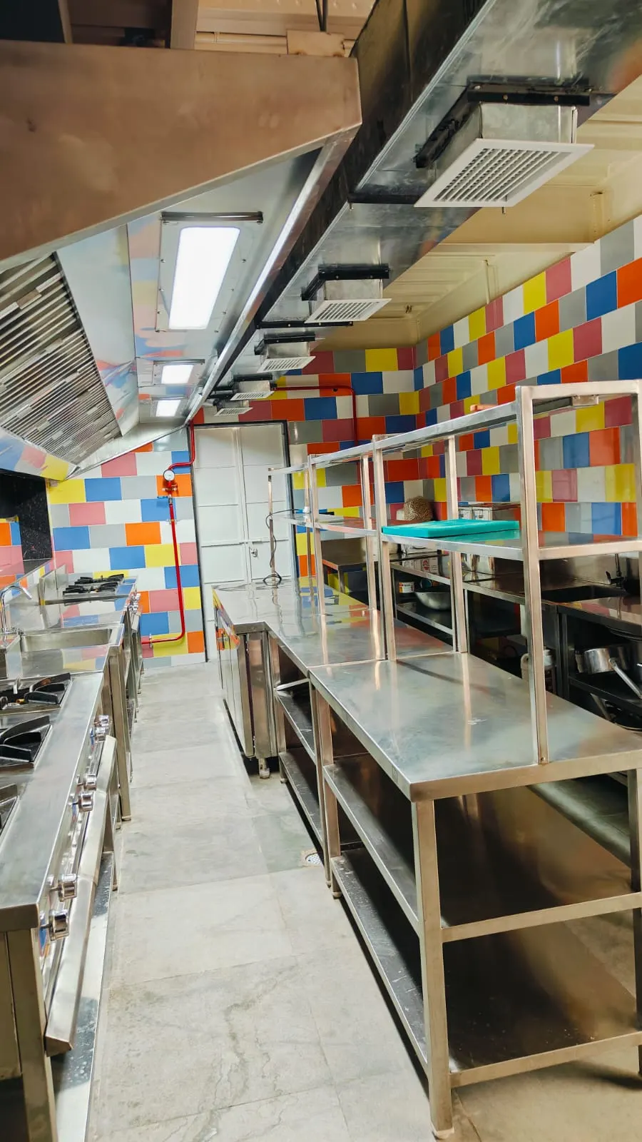 Exhaust hood with lighting over work tables in a tiled kitchen
