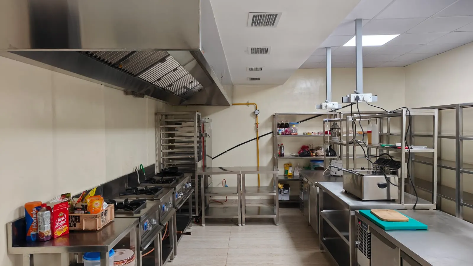 Complete commercial kitchen with exhaust hood, cooking line and work tables