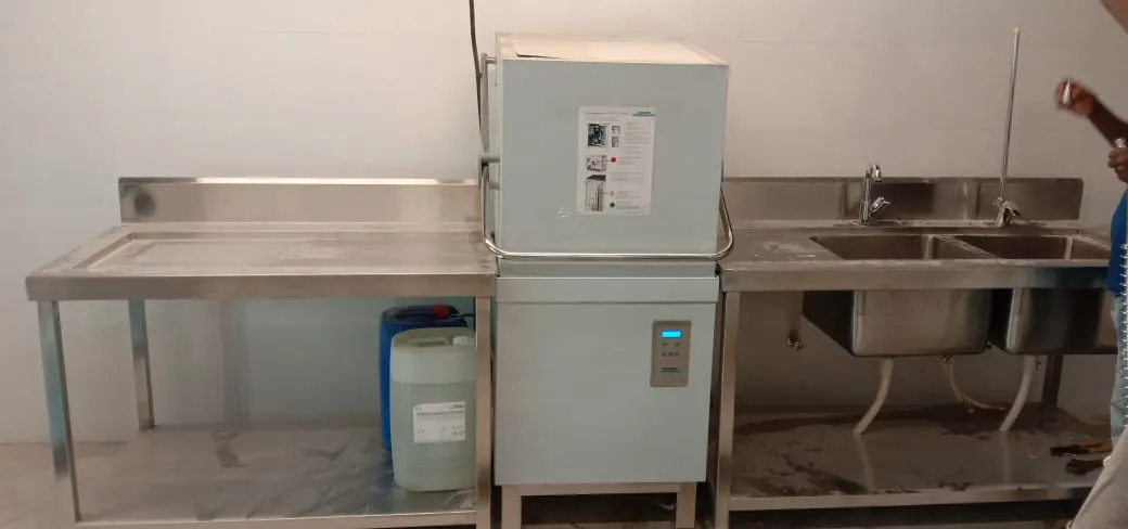 Hood type dishwasher with inlet and outlet tables
