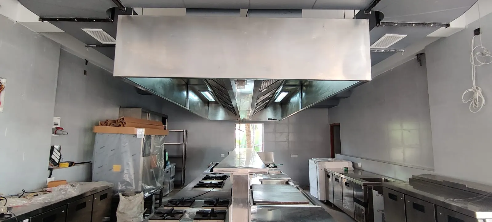 Large island exhaust hood being installed in a commercial kitchen