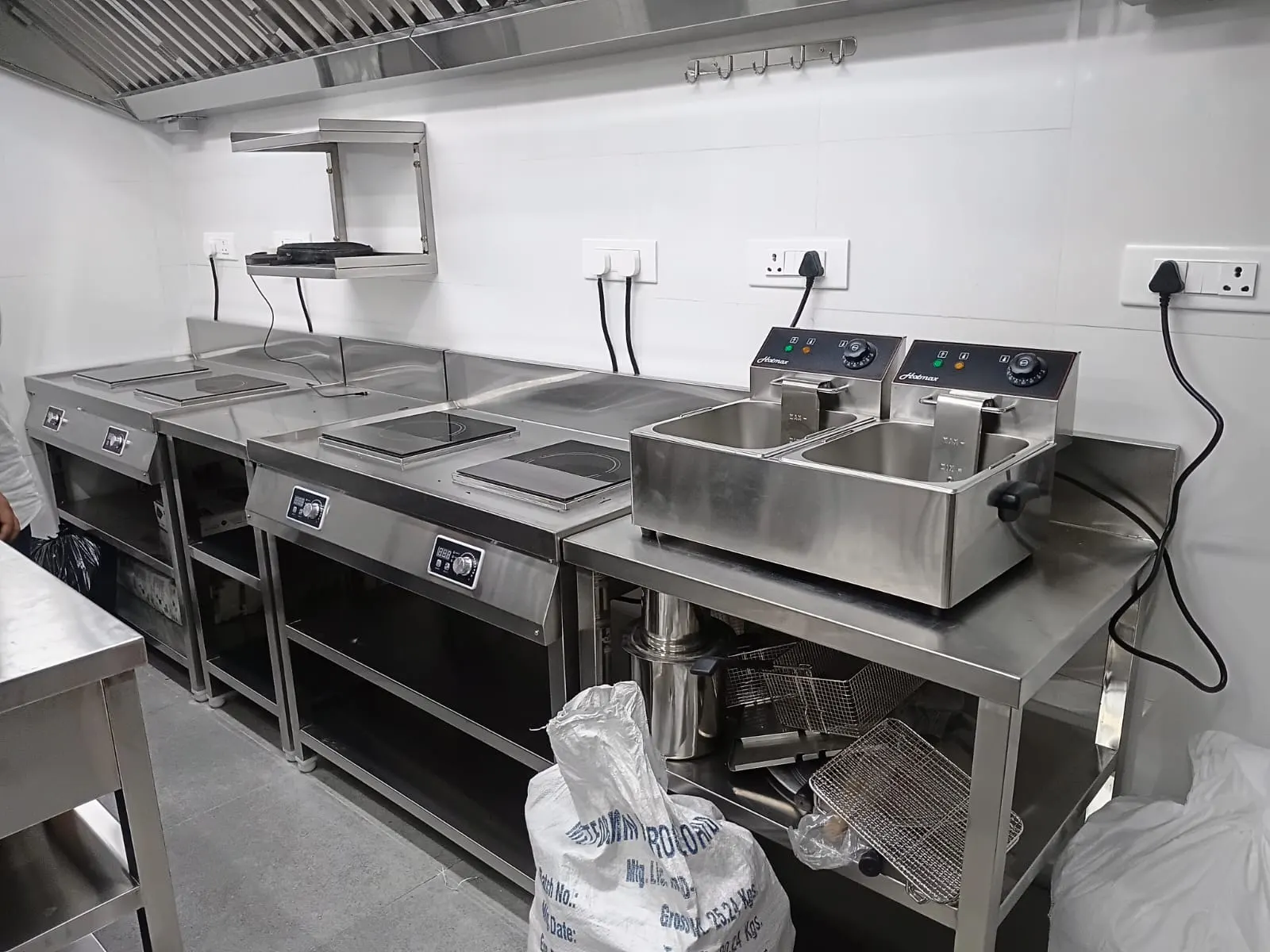 Double table top fryer and induction cooktops on a stainless steel counter