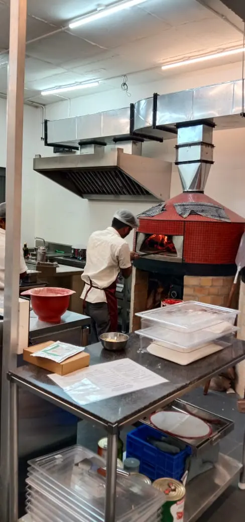 Tandoor and work table under an exhaust hood in a restaurant kitchen